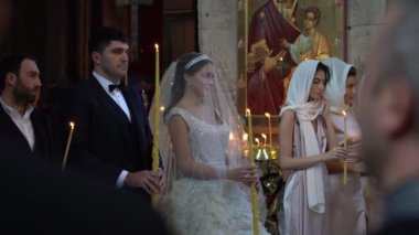 MTSKHETA, GEORGIA - 27 Ekim 2018: Gelin ve damat ellerinde mumlarla Tiflis, Gürcistan yakınlarındaki tarihi Mtskheta kasabasındaki Hıristiyan Ortodoks Kilisesinde evlendiler