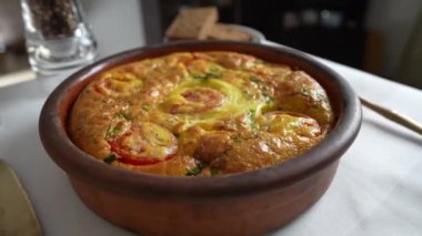 Sebzeli frittata ile seramik kase, basit vejetaryen yemeği. Yumurtalı frittata, domates, biber, soğan, peynir ve yeşil sarımsak yaprakları masada, döndür, kapat. Sağlıklı yumurta omleti.