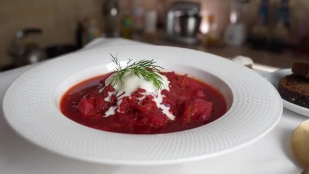 传统的乌克兰红汤或罗宋汤配红甜菜 胡萝卜 卷心菜 豆子在白碗上 一盘红甜菜汤罗宋汤轮流放在桌上 传统乌克兰食品 — 图库视频影像