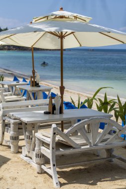 Ahşap masa ve deniz suyunun yanındaki boş sahil kafesinde sandalyeler. Koh Phangan Adası, Tayland