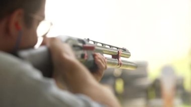 Adam atış poligonundaki hedeflere tüfekle ateş ediyor, yaklaşın, yavaş çekim. Atış talimi yaparken pompalı tüfekle ateş eden adamın arka görüntüsü