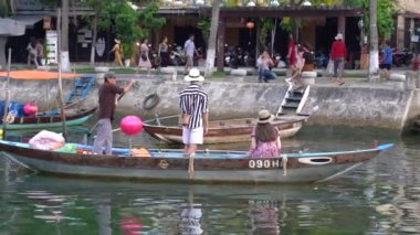 Hoi An, Vietnam - 13 Haziran 2020: Vietnamlılar Hoi Nehri kıyısındaki ahşap bir teknede yüzüyorlar.