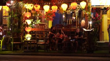 Hoi An, Vietnam - 15 Mart 2020: Avrupalı turistler Hoi An kasabasında nehir kenarında dinleniyorlar. Hoi An, Vietnam 'da Da Nang yakınlarında bir şehirdir ve iyi korunmuş eski kasabasıyla ünlüdür.