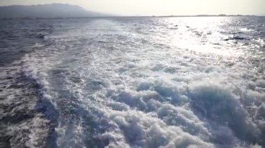 Hızlı yat teknesiyle mavi okyanus suyu dalgası pervane yıkama köpüğünü uyandırıyor. Geminin hareketi sırasında su damlaları sıçrıyor. Seyahat ve doğa kavramı. Yavaş çekim