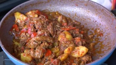 Soğanlı kızartma tavası, limon otu, kırmızı biber ve sığır eti, yakından. Endonezya 'da. Sambal Goreng Ati Kentang, Endonezya mutfağı, baharatlı biftek buluşması ve limon otu yaprağı ve kırmızı biberli patates garnitürü.