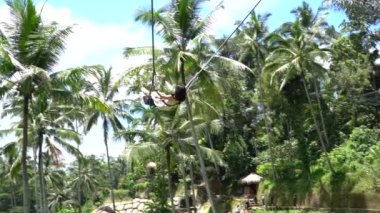 Bali, Indonezya - 11 Mart 2019: Turist ormanda salıncakta sallanıyor. Ubud, Endonezya yakınlarındaki Bali adasının yağmur ormanlarında sallanan insanlar, ağır çekim