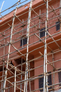 Ev deki bambu iskelesi, tadilat. Bina, pembe duvar ve pencere iskelesi. İnşaatta iskele sistemi. Jaipur, Hindistan