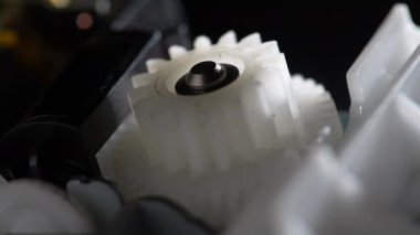 Vitesler mekanik bir cihazda dönüyor. Soyut dönen makine beyaz plastik dişliler. Çarklı tekerlek mekanizması, kapat, makro