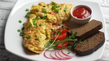 Beyaz ahşap zemin üzerinde soğan, domates, biber, yumurta ve peynirle doldurulmuş omlet ve çatal. Kahvaltı için sağlıklı diyet yemeği. Lezzetli sabah yemeği. Üst görünüm, kapat, döndür