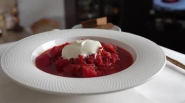 Geleneksel Ukrayna kırmızı çorbası veya kırmızı pancar, patates, havuç, lahana, beyaz kasede fasulye, yakın çekim. Bir tabak kırmızı pancar çorbası çorbası masada döner. Geleneksel Ukrayna yemekleri