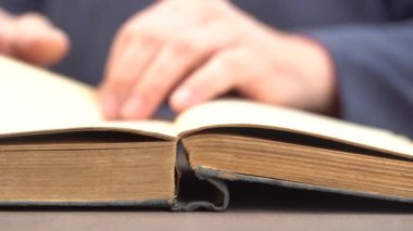 Evde ya da kütüphanede kitap okuyan bir adamın eli. Eski bir kitabın sayfalarını çevirip kapat.