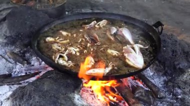 Satıcı, Doğu Afrika 'daki Tanzanya' nın Zanzibar adasındaki yerel bir sokak gıda pazarında büyük bir kızartma tavasında sebze yağında mürekkep balığı kızartıyor. Kapat.