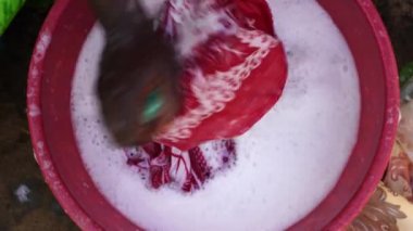 Afrikalı kadın elleri Doğu Afrika, Tanzanya 'daki Zanzibar adasının yakınındaki bir sokakta çarşafta çamaşır yıkıyor. Kirli giysilerin lekesini deterjanla elle yıka. Kapat.