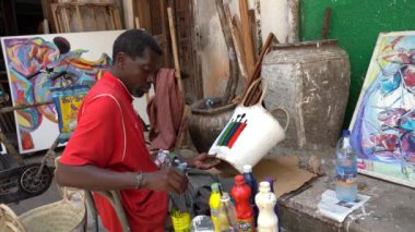 Zanzibar, Tanzania - november 03, 2019 : African man on the street paints a basket for sale for tourists in the Stone Town on the island of Zanzibar, Tanzania, East Africa