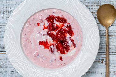 Kırmızı çilekli beyaz tabak ve ahşap bir masada yoğurt, yakın çekim, üst manzara