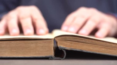 Evde ya da kütüphanede kitap okuyan bir adamın eli. Eski bir kitabın sayfalarını çevirip kapat.