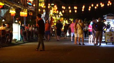 Hoi An, Vietnam - 15 Mart 2020: Avrupalı turistler eski Hoi An şehrinin merkezindeki restoranların yanında nehir boyunca yürüyorlar.
