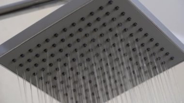 Banyodaki bej kaplamalı duş başlığından akan su. Basit stil ve modern ev dekorasyonu. Kapat.
