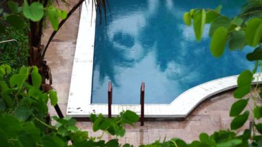 Tropik yaz yağmurları, yüzme havuzuna düşen yağmur damlaları Phu Quoc Adası, Vietnam, Güneydoğu Asya 'daki deniz kıyısında. Doğa ve çevre kavramı