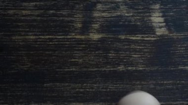 Chicken egg rotates on a wooden table, close up, top view
