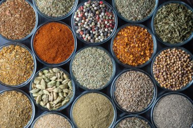Arka planda yemek pişirmek için çeşitli aromatik baharatlar, tohumlar ve kuru otlar, cam kaselerde, yakın plan, üst görüş