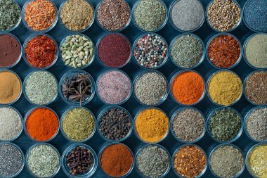 Arka planda yemek pişirmek için çeşitli aromatik baharatlar, tohumlar ve kuru otlar, cam kaselerde, yakın plan, üst görüş