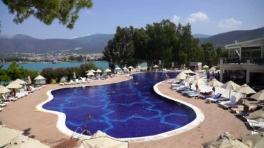 Didim, Türkiye - Eylül 05, 2019: İnsanlar Türkiye 'nin Didim kentindeki tatil otelinde denizin yanındaki havuzda yüzüyor ve güneşleniyor. Tatil ve eğlence kavramı