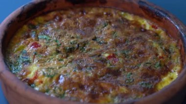 Sebzeli frittata ile seramik kase, basit vejetaryen yemeği. Tahta masada domates, biber, soğan ve peynirli frittata, yakın çekim. İtalyan omleti, sırayla.