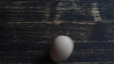 Tavuk yumurtası ahşap bir masada döner, yakın plan, üst manzara