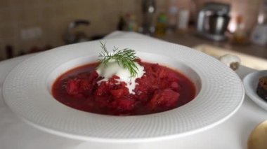 Geleneksel Ukrayna kırmızı çorbası veya kırmızı pancar, patates, havuç, lahana, beyaz kasede fasulye, yakın çekim. Bir tabak kırmızı pancar çorbası çorbası masada döner. Geleneksel Ukrayna yemekleri