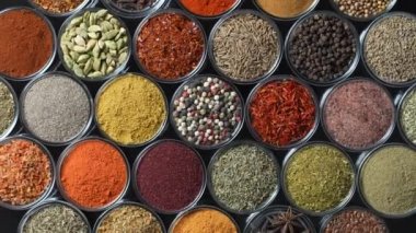 Arka planda yemek pişirmek için çeşitli aromatik baharatlar, tohumlar ve kuru otlar. Smal cam kaselerde dönüyorlar, kapatıyorlar, üstten bakıyorlar.