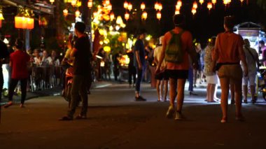 Hoi An, Vietnam - 15 Mart 2020: Avrupalı turistler eski Hoi An şehrinin merkezindeki restoranların yanında nehir boyunca yürüyorlar.