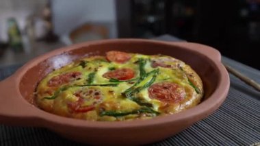 Sebzeli frittata ile seramik kase, basit vejetaryen yemeği. Yumurtalı frittata, domates, biber, soğan, peynir ve yeşil sarımsak yaprakları masada, döndür, kapat. Sağlıklı yumurta omleti.