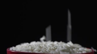 Beyaz pirinç yere düşer ve kaseyi masaya koyar, kapat. Siyah arka planda çekim yapmak. Yavaş çekim