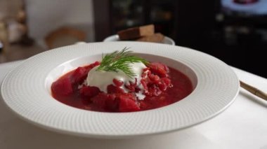 Geleneksel Ukrayna kırmızı çorbası veya kırmızı pancar, patates, havuç, lahana, beyaz kasede fasulye, yakın çekim. Bir tabak kırmızı pancar çorbası çorbası masada döner. Geleneksel Ukrayna yemekleri
