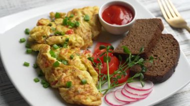 Beyaz ahşap zemin üzerinde soğan, domates, biber, yumurta ve peynirle doldurulmuş omlet ve çatal. Kahvaltı için sağlıklı diyet yemeği. Lezzetli sabah yemeği. Üst görünüm, kapat, döndür