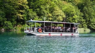 Plitvice Gölleri, Hırvatistan - 30 Ağustos 2021: İnsanlar yaz aylarında Hırvatistan, Orta Avrupa, seyahat ve doğa kavramları ile Plitvice Gölleri kıyıları boyunca turistik bir tekneye biniyor