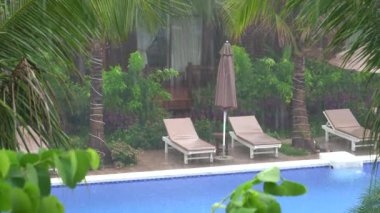 Tropik yaz yağmurları, yüzme havuzuna düşen yağmur damlaları Phu Quoc Adası, Vietnam, Güneydoğu Asya 'daki deniz kıyısında. Doğa ve çevre kavramı