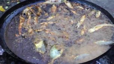 Satıcı, Doğu Afrika 'daki Tanzanya' nın Zanzibar adasındaki yerel bir sokak gıda pazarında büyük bir kızartma tavasında sebze yağında balık kızartıyor. Kapat.