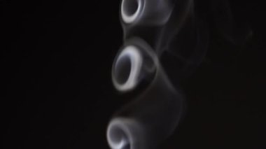 White smoke on black background in slow motion. White steam spins and rises