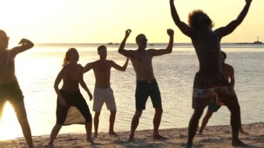 KOH PHANGAN, THAILAND - 18 Şubat 2019: günbatımında cennet adasındaki deniz suyu yakınlarındaki tropik plajda dans eden genç insanlar. Yaz kavramı. Tatil seyahati. Yavaş çekim
