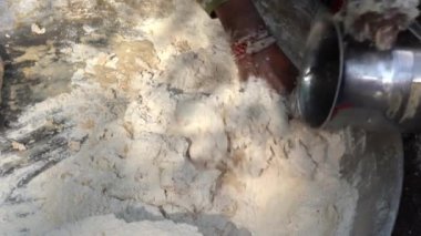 Hintli yaşlı kadın Udaipur, Rajasthan, Hindistan 'daki yerel pazarın yakınındaki avluda chapati için hamur hazırlıyor. Kapat.