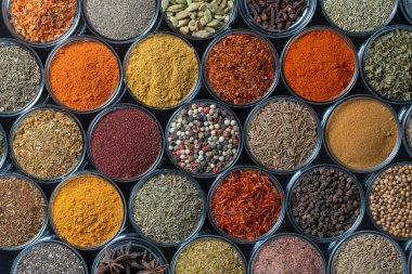 Arka planda yemek pişirmek için aromatik baharatlar, tohumlar ve kuru otlar küçük cam kaselerde, yakın plan, üst görüş