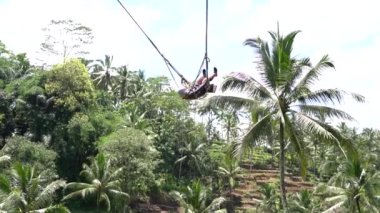 Bali, Indonezya - 11 Mart 2019: Asyalı kız ormanda salıncakta sallanıyor. Ubud, Endonezya yakınlarındaki Bali adasının yağmur ormanlarında sallanan insanlar, ağır çekim