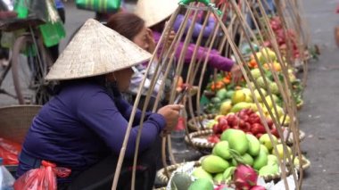 Hanoi, Vietnam - Mart 01, 2020: Kadınlar Hanoi, Vietnam 'daki eski bir kasabanın sokak gıda pazarında meyve ve sebze satıyorlar