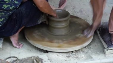 Close-up of a woman potters rotate a wheel with her foot and making a beautiful clay pot with her hands at pottery manufacture in the Old Town Hoi An, Vietnam