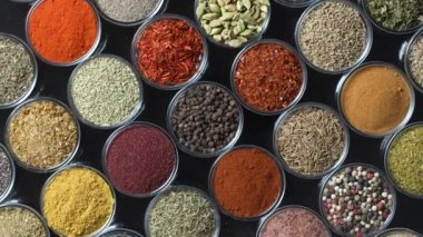 Arka planda yemek pişirmek için çeşitli aromatik baharatlar, tohumlar ve kuru otlar. Smal cam kaselerde dönüyorlar, kapatıyorlar, üstten bakıyorlar.