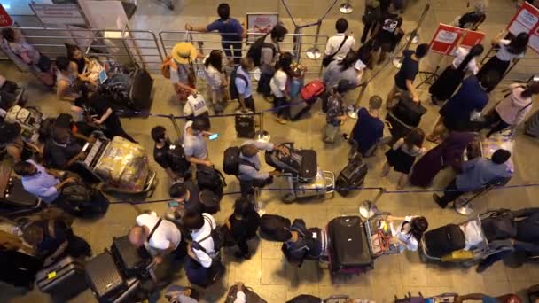 バンコク 2019年2月26日 タイのバンコクにあるドンムアン空港での出発のためのチェックインカウンターでの列に荷物スタンドと一緒に乗客の群衆 トップビュー — ストック動画