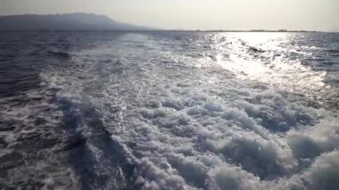 Hızlı yat teknesiyle mavi okyanus suyu dalgası pervane yıkama köpüğünü uyandırıyor. Geminin hareketi sırasında su damlaları sıçrıyor. Seyahat ve doğa kavramı. Yavaş çekim