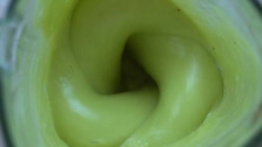 Meyveler sağlıklı yeşil bir meyve püresi ile harmanlanmış. Taze muz ve avokado kokteyli. Sağlıklı beslenme ve yaşam tarzı kavramı. Yakın çekim, yavaş çekim, üst görünüm